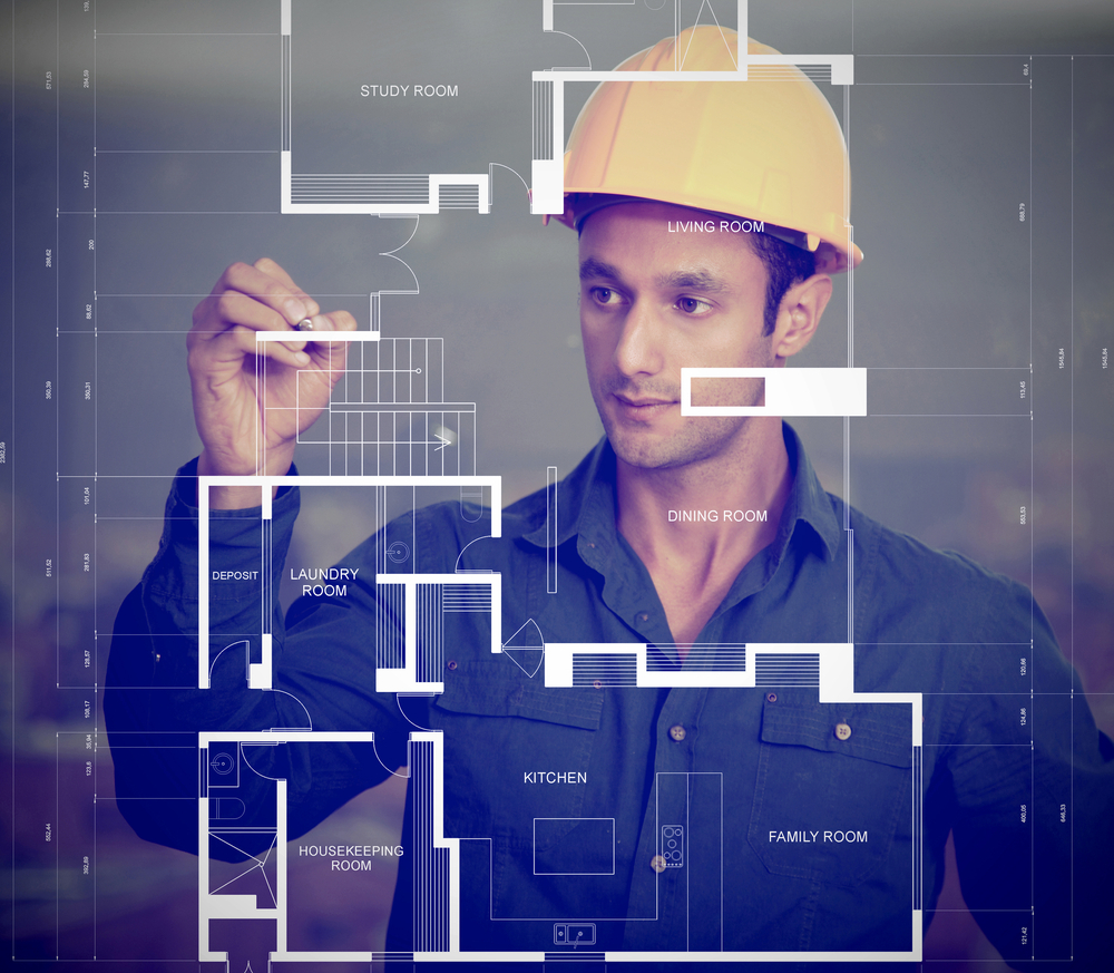 Construction worker wearing a helmet and sketching blueprints Construction worker wearing a helmet and sketching blueprints